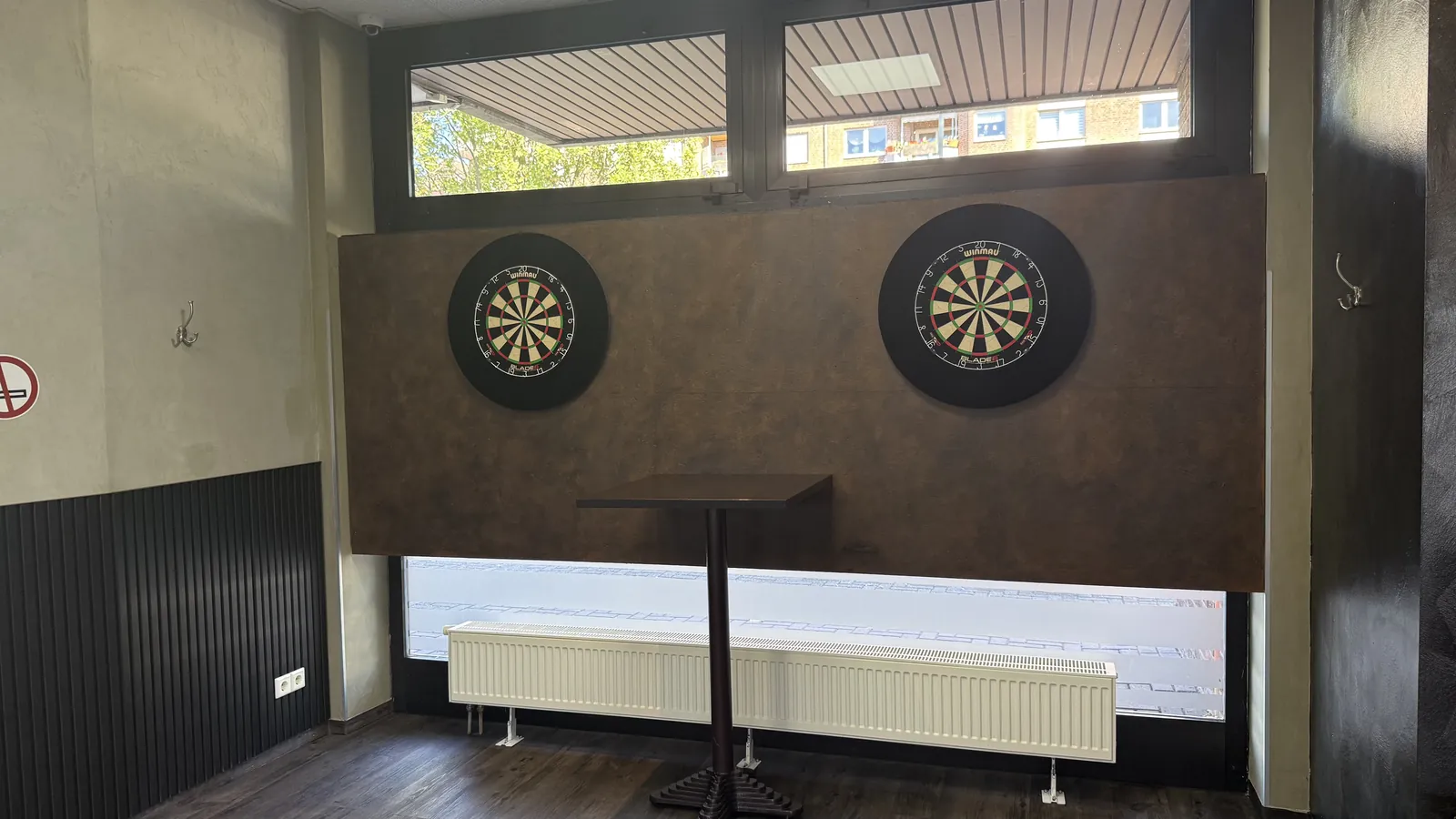 Zwei Steel-Dart-Scheiben an der braunen Wandverkleidung der Sportsbar Voerde, davor ein Stehtisch