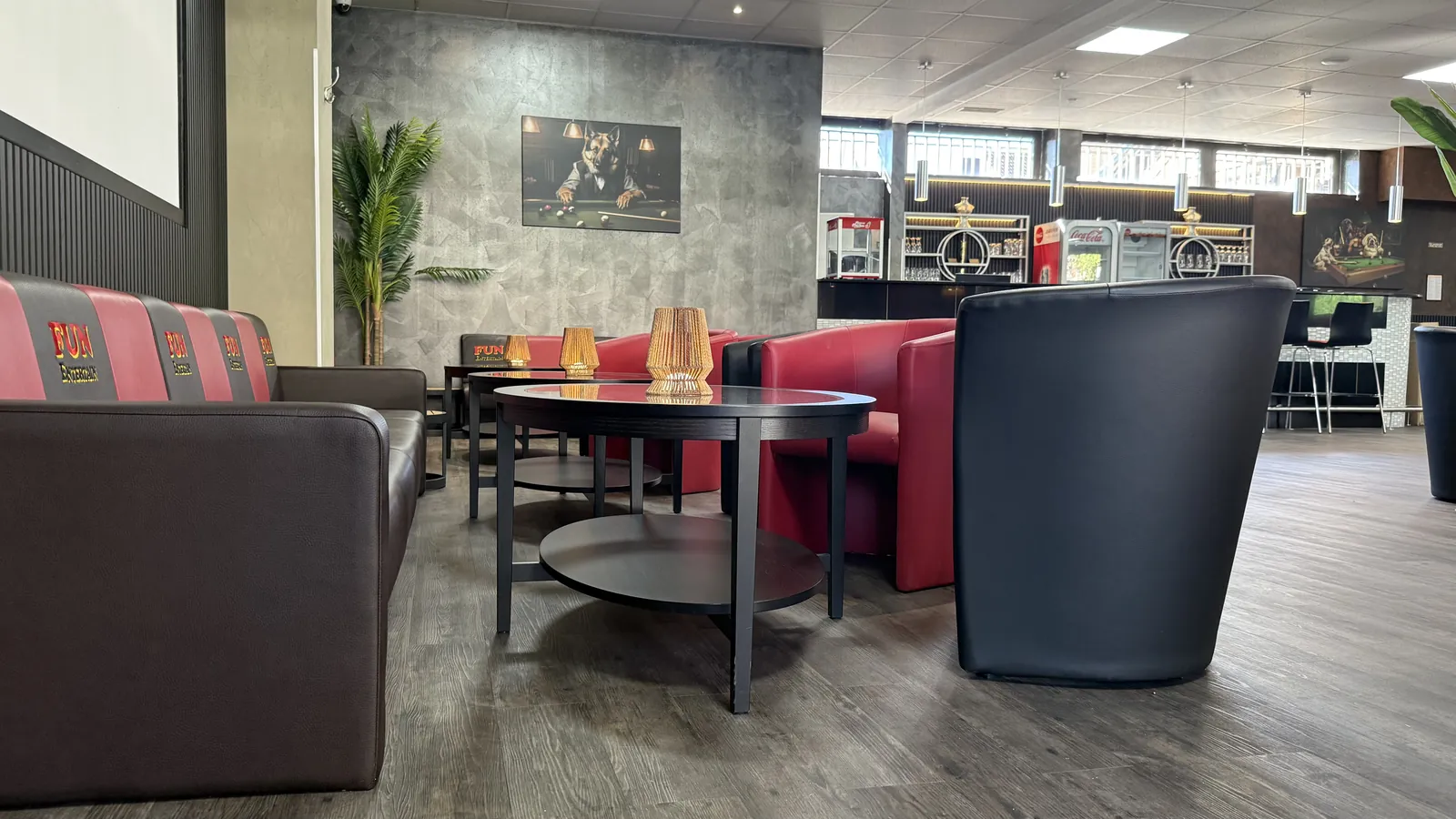 Sitzecke der Sportsbar Voerde mit braunem Sofa, roten Sesseln und rundem Glastisch mit Windlichtern, an der Wand ein Billardbild